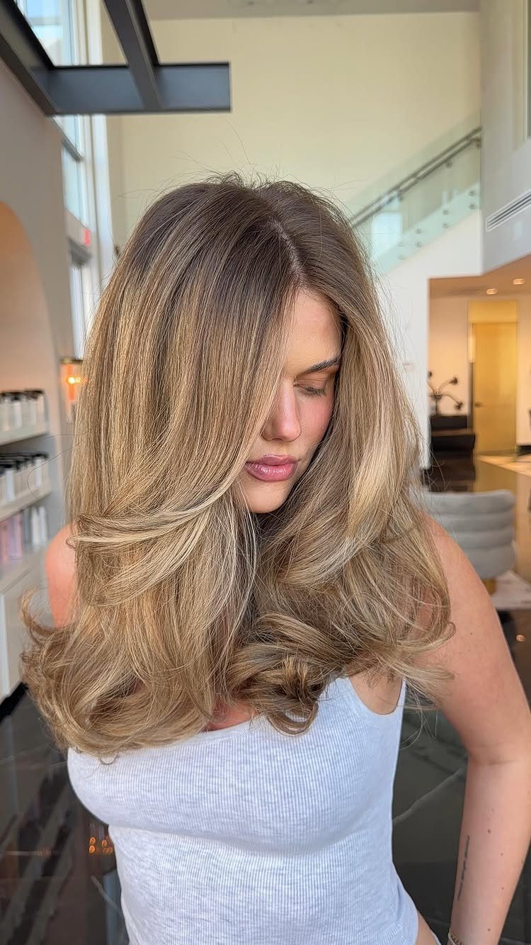 Woman with highlighted, layered hair and curled ends in a bright salon