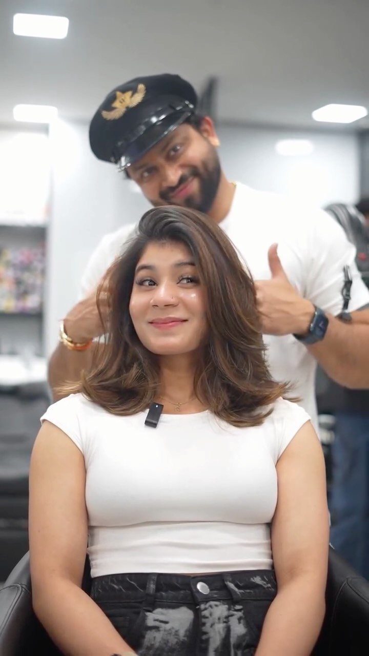 Woman showing shoulder-length brown waves swept across a deep side part