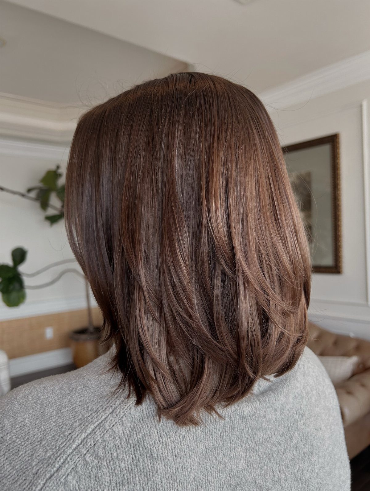 Brown shoulder-length hair with soft layers and tapered ends over a gray sweater