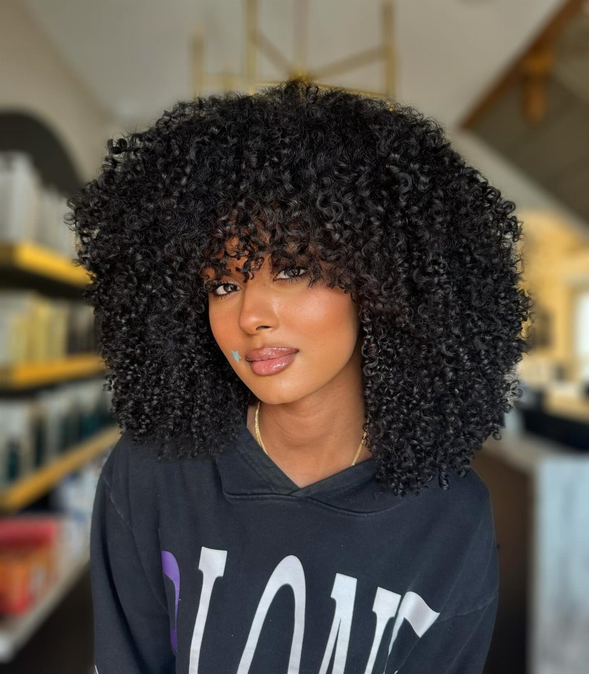 Person posing with a large, rounded afro of tight black curls