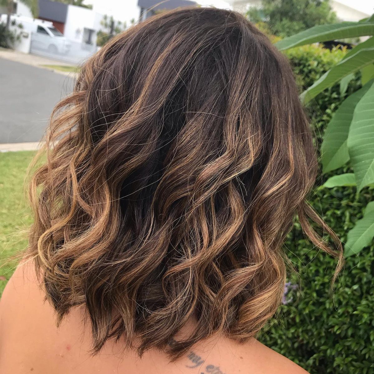 Medium-length highlighted hair with layered, loose waves curling at the ends