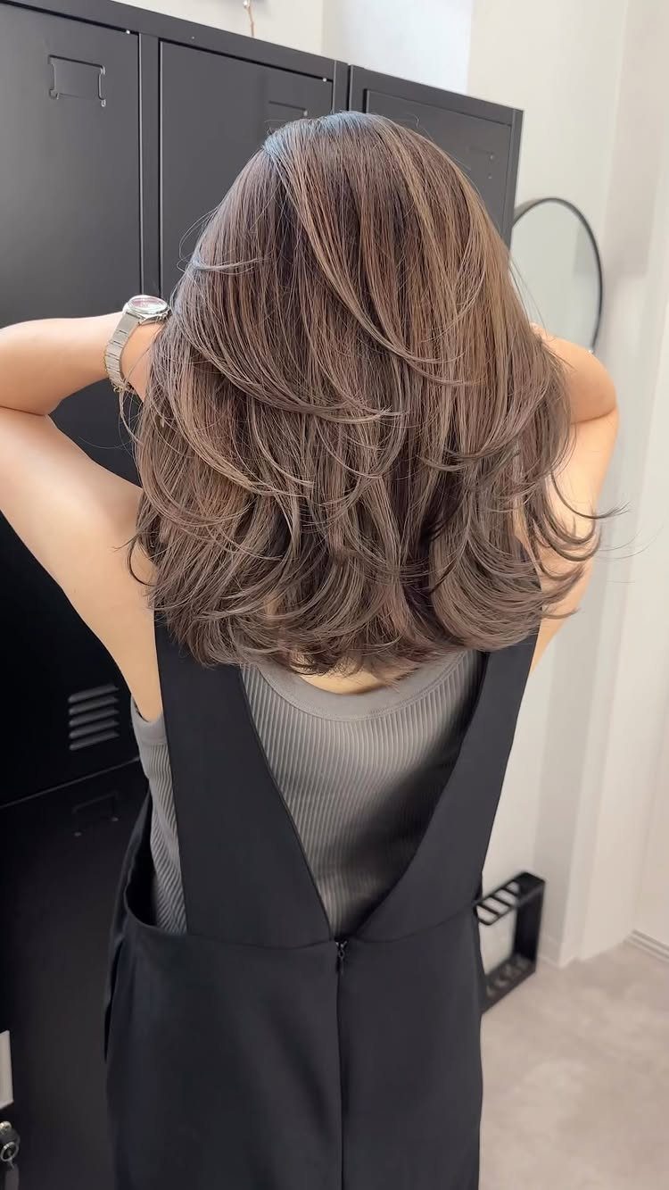 Shoulder-length brown hair with layered, softly waved ends seen from behind