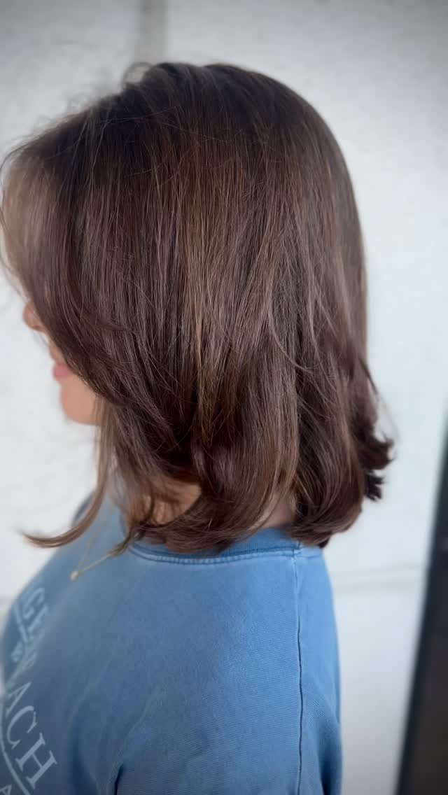 Shoulder-length dark brown layered haircut with wispy feathered ends